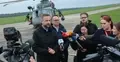Władysław Kosiniak-Kamysz odpowiada na pytania dziennikarzy na płycie lotniska. W tle śmigłowiec