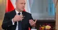 Karol Nawrocki gestykuluje, w tle flaga Polski