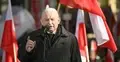 Jarosław Kaczyński przemawia i gestykuluje, w tle polskie flagi