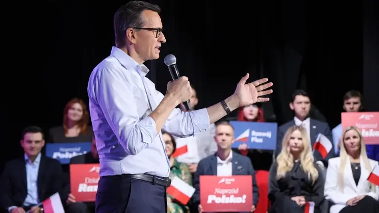 Mateusz Morawiecki przemawia do mikrofonu, w tle ludzie