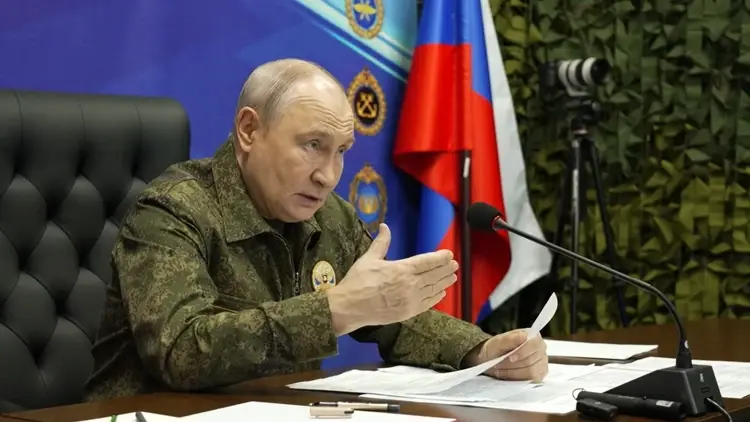 Władimir Putin w mundurze wojskowym, w tle flaga Rosji