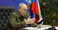 Władimir Putin w mundurze wojskowym, w tle flaga Rosji