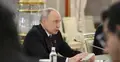 Władimir Putin przemawia do mikrofonu siedząc przy stole