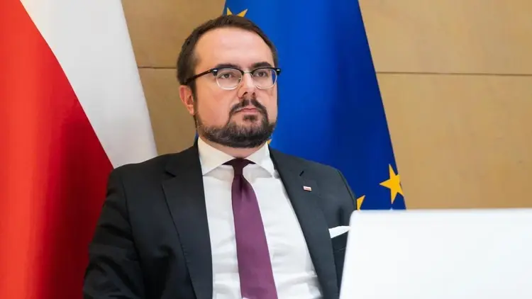Paweł Jabłoński, w tle flaga Polski i UE