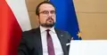 Paweł Jabłoński, w tle flaga Polski i UE