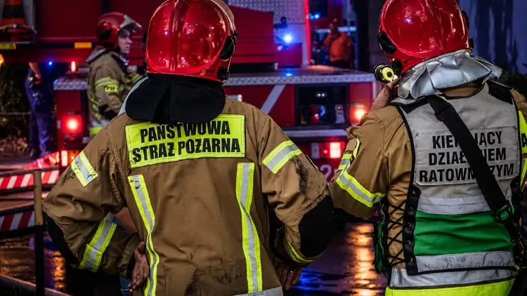 strażacy i wóz strażacki w nocy