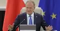 Donald Tusk przemawia i gestykuluje na Radzie Ministrów. W tle flaga Polski i UE