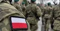 Polski żołnierz z biało-czerwoną naszywką na mundurze, w tle grupa żołnierzy Wojska Polskiego.