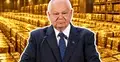Adam Glapiński przy mównicy na tle skarbca wypełnionego sztabkami złota