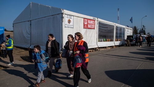 uchodźcy przy namiocie Caritas