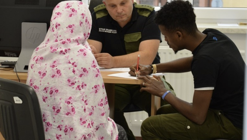 Imigranci ze funkcjonariuszem Straży Granicznej