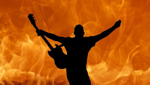 Ogień i sylwetka człowieka z gitarą