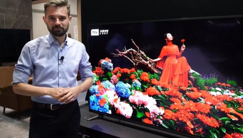 Dr Maciej Kawecki na tle telewizora 8K