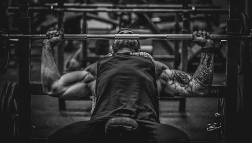 Mężczyzna ćwiczący sztangą na siłowni. Ilustracja poglądowa