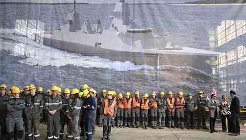Pracownicy PGZ Stoczni Wojennej w Gdyni. W tle obraz fregaty Miecznik.