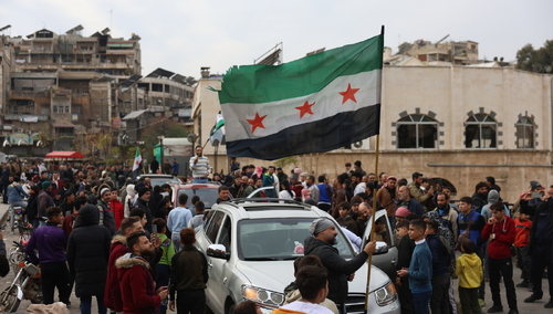Ludzie machają flagą syryjskiej opozycji po tym, jak bojownicy opozycji przejęli kontrolę nad miastem Hama w Syrii, 7 grudnia 2024 r.