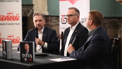 Trzech mężczyzn przy stole z postawionymi książkami