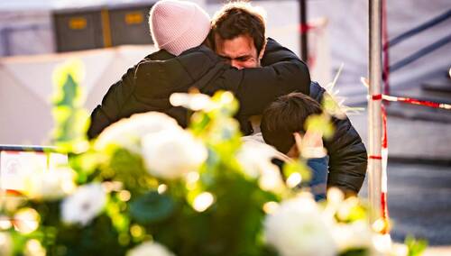 Ludzie pocieszają się nawzajem w pobliżu baru i salonu Le Constellation, gdzie wybuchł pożar