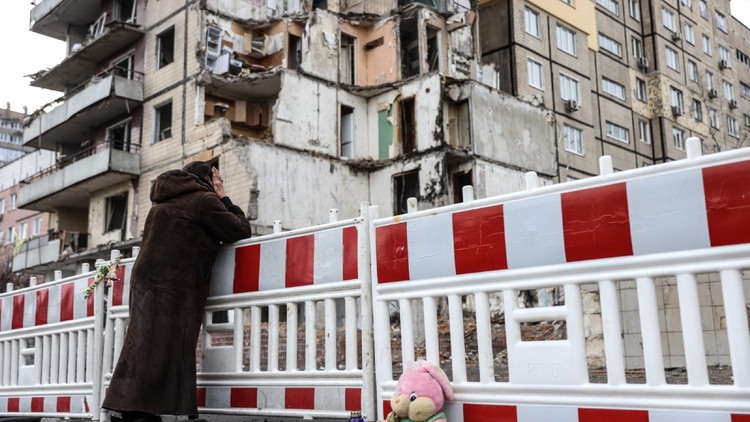 Kobieta stoi przed zniszczonym blokiem w Dnieprze.