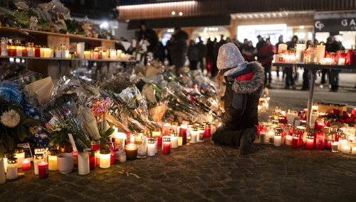 Dziewczynka klęczy obok zapalonych świec w miejscu pamięci ofiar śmiertelnego pożaru w barze „Le Constellation” w Crans-Montanie w Szwajcarii.