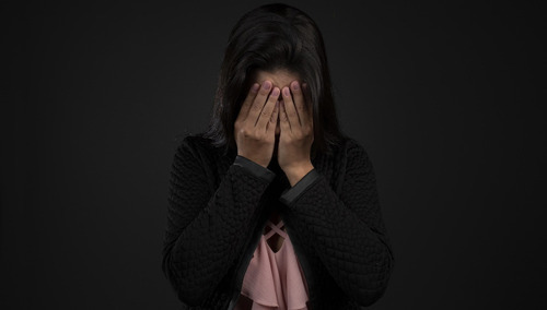 Kobieta zasłaniająca dłońmi twarz