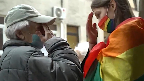 starsza pani modli się z tęczową aktywistką