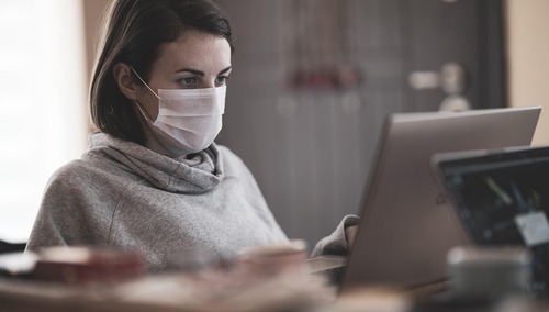 Kobieta w maseczce przed laptopem