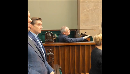 Bartłomiej Sienkiewicz siedzący podczas hymnu