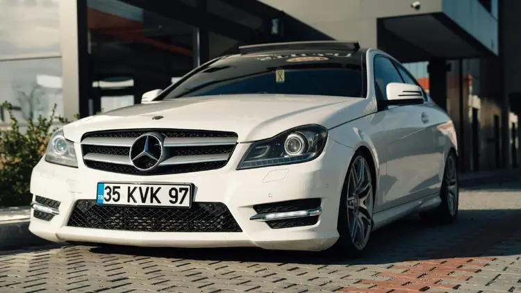 Biały mercedes stojący przed budynkiem