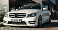 Biały mercedes stojący przed budynkiem