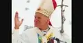 Papież Jan Paweł II unoszący dłoń, krzyż w tle