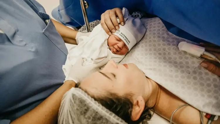 Położna podaje matce jej nowo narodzone dziecko