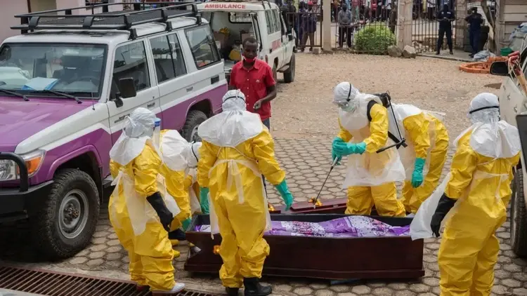pracownicy sanitarni przy odkażaniu trumny z ciałem ofiary wirusa ebola w buni w kongo