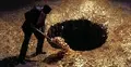 Deficyt. Mężczyzna wrzuca pieniądze do czarnej dziury