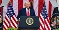 Donald Trump na tle amerykańskich flag przemawia do mikrofonu