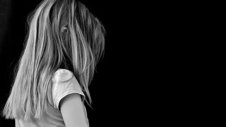 Czarno-biała fotografia przedstawiająca dziewczynkę zwróconą do tyłu
