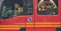 Strażacy w wozie strażackim wyglądają przez okno