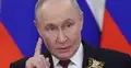 Władimir Putin gestykuluje palcem na tle rosyjskich flag