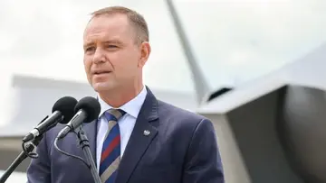 Karol Nawrocki przemawia do mikrofonu na tle samolotu F-35