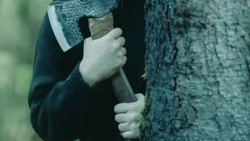 Człowiek z siekierą kryjący się za drzewem