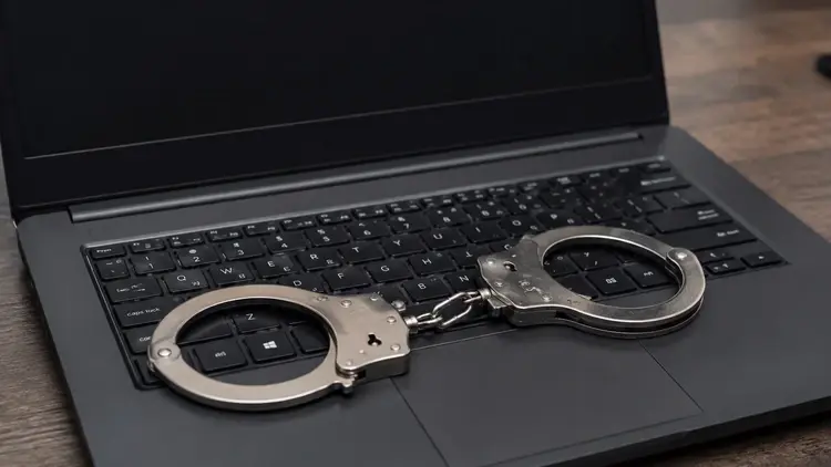 Otwarty laptop z kajdankami na klawiaturze