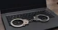 Otwarty laptop z kajdankami na klawiaturze