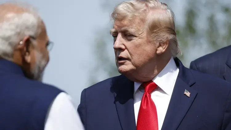 Donald Trump w garniturze, obok stoi mężczyzna