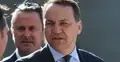 Radosław Sikorski w garniturze, w tle mężczyzna