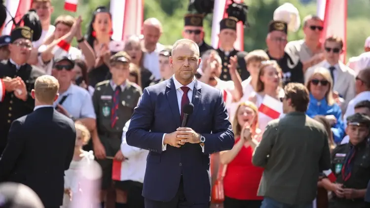 Karol Nawrocki przemawia do mikrofonu na zgromadzeniu. W tle tłum ludzi