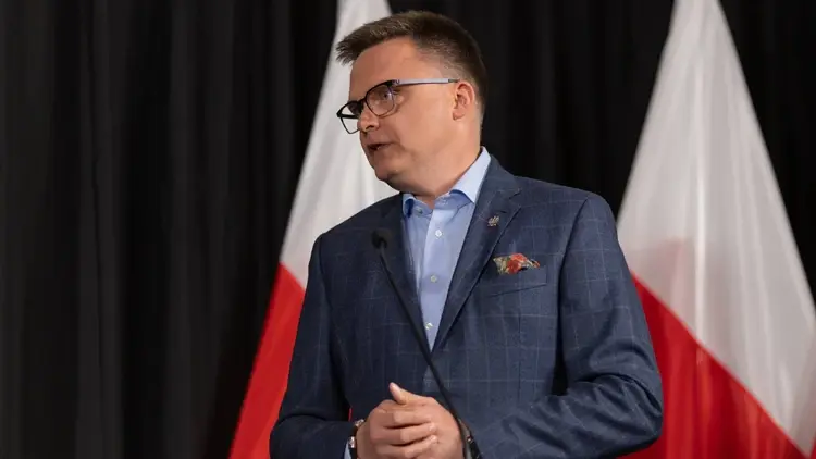 Szymon Hołownia. W tle polskie flagi