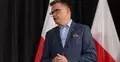 Szymon Hołownia. W tle polskie flagi