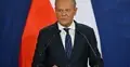 Donald Tusk przemawia do mikrofonu. W tle polska flaga