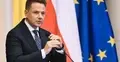 Rafał Trzaskowski trzyma mikrofon. W tle flaga Polski i UE