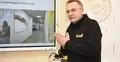 Andrij Sadowy w ciemnej bluzie gestykuluje. W tle ekran z prezentacją